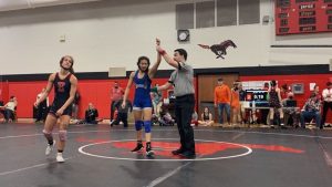 Arms raised, junior Emily Anderson cheers after winning a match