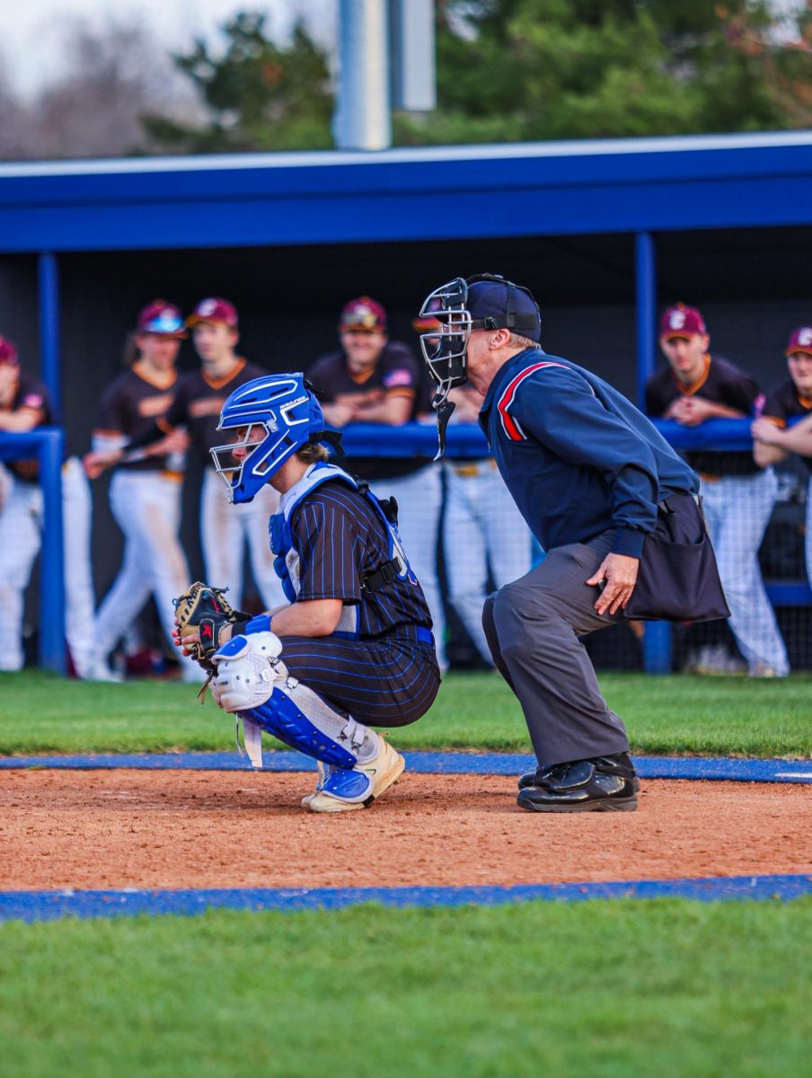 Senior Alex Billman awaiting pitch while umpire stands over him.