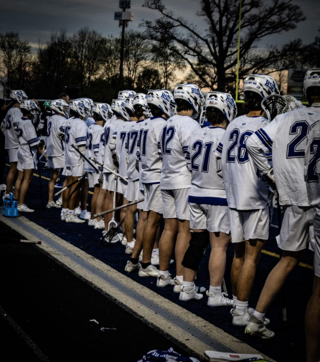 Hse boys lacrosse team cheers on their team on the field.