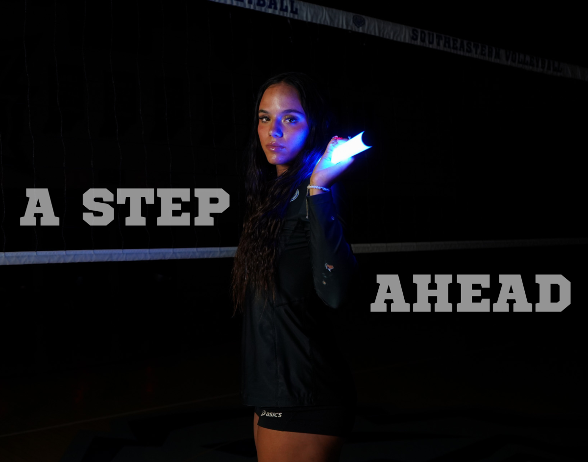 Standing in front of a volleyball net in a dark gym, senior Kaylyn Bostrom-Christy stands serious for the Southeastern Media Network varsity volleyball media day. Bostrom-Christy plans to graduate at semester as well. 